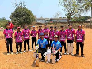 Full youth cricket team in pink Rajasthan Lion jerseys and blue MP Tiger jerseys posing on an open cricket ground with padded batsmen kneeling in front.